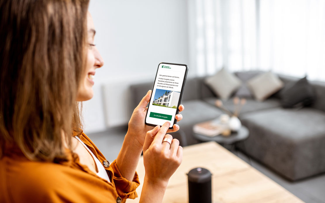 Das Bild zeigt eine junge Frau, die auf einem Smartphone die Seite mit dem Thurgauer Eigenheimindex auf der TKB Website anschaut.